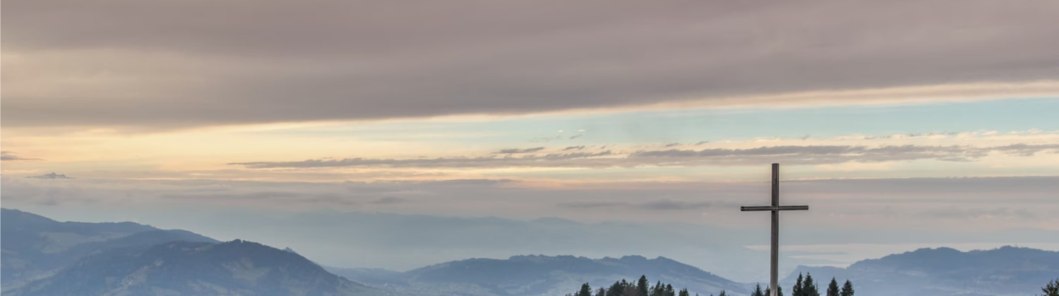 a big cross with mountains on the background